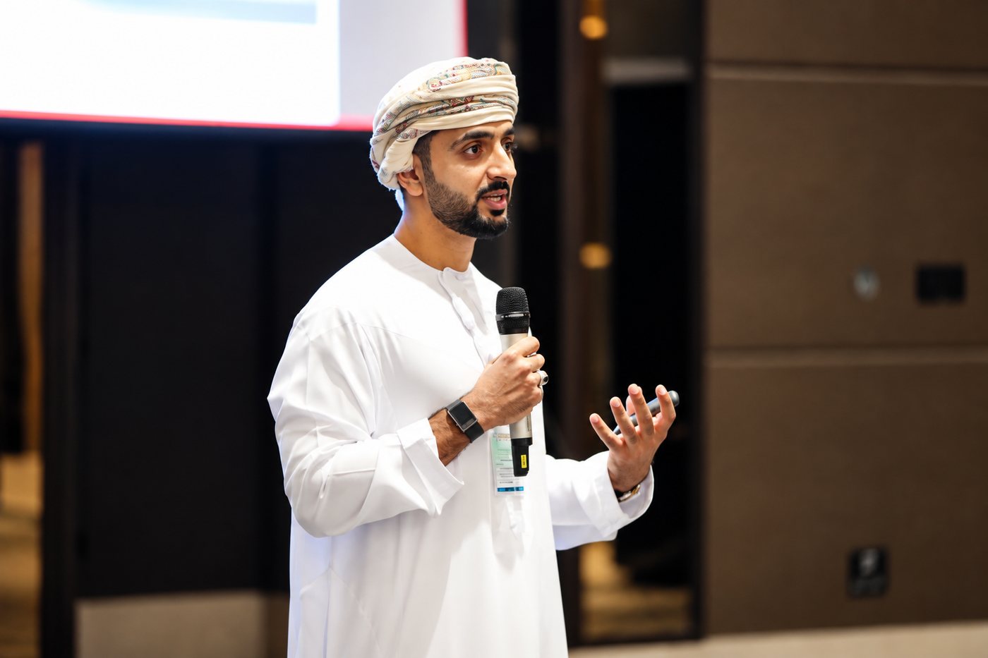 Saif Al Manji speaking to a room, holding a microphone